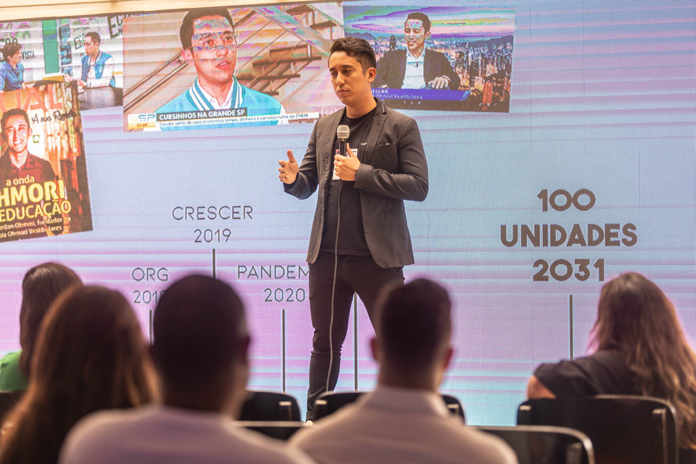 Marco no palco diante de um telão com a linha do tempo da Ohmori até 100 unidades em 2031