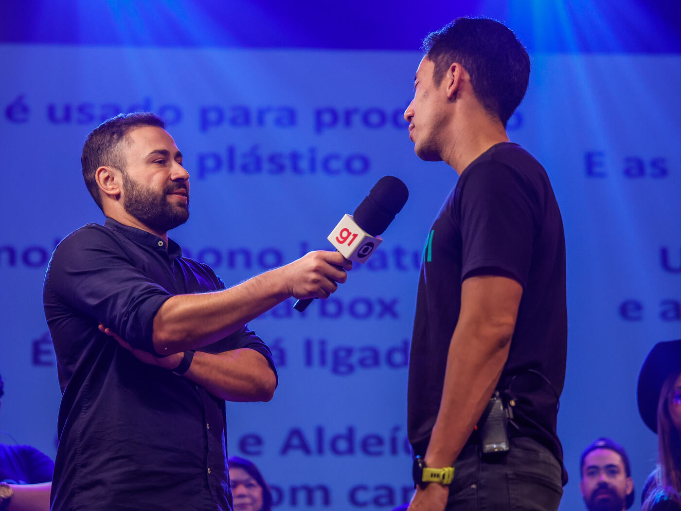 Repórter com microfone do g1 entrevista Marco no palco do Pancadão do ENEM